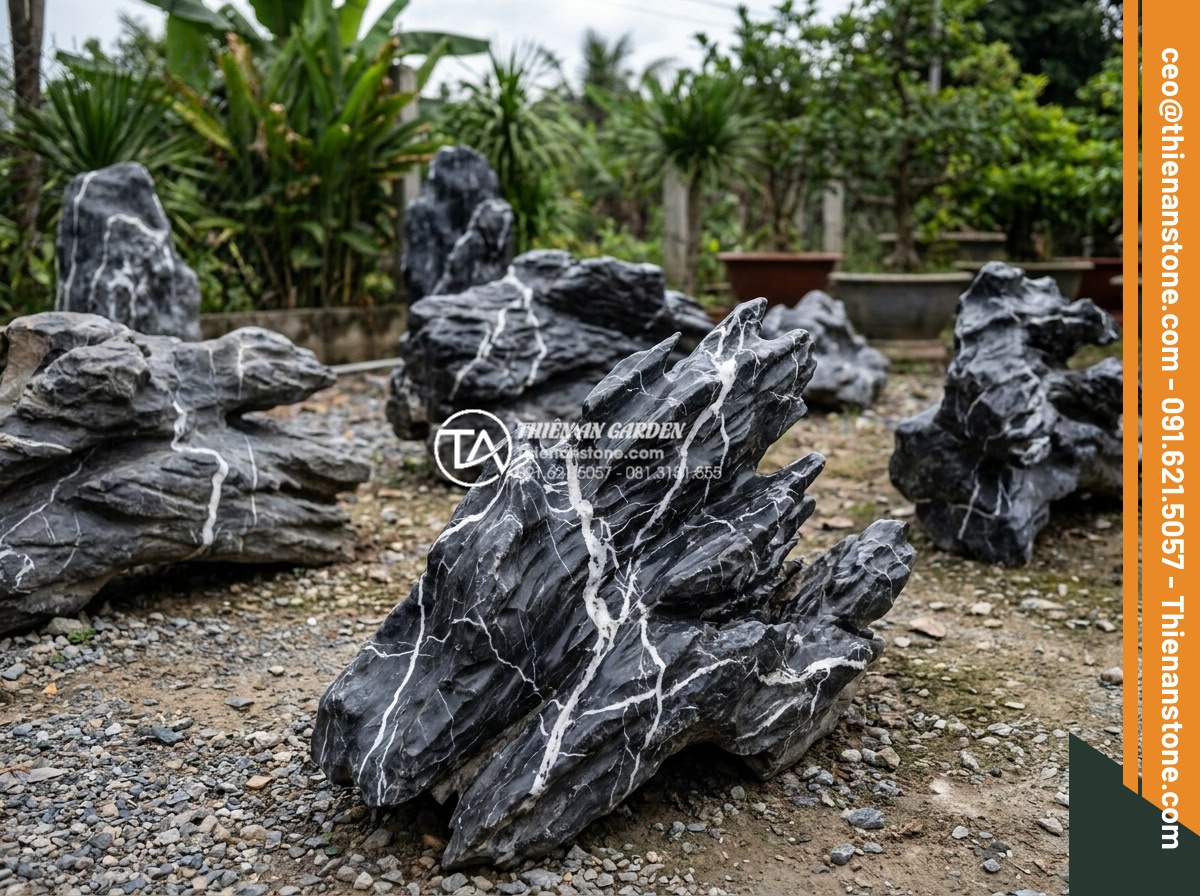 Đá Cảnh Tự Nhiên - Collection of different natural ornamental stones displayed in an outdoor stone 