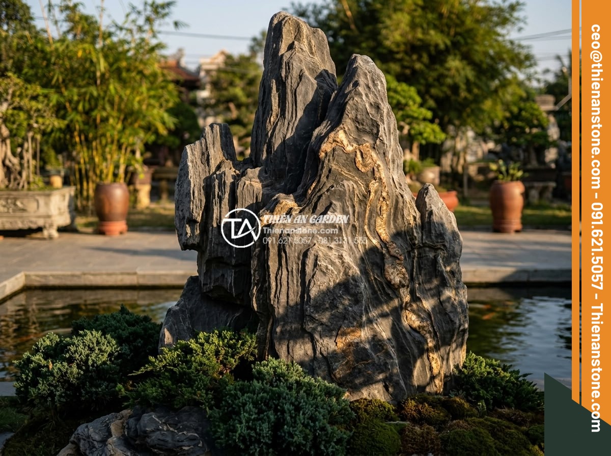 Đá Cảnh Tự Nhiên - Tall vertical natural ornamental stone standing in a landscaped garden with low 