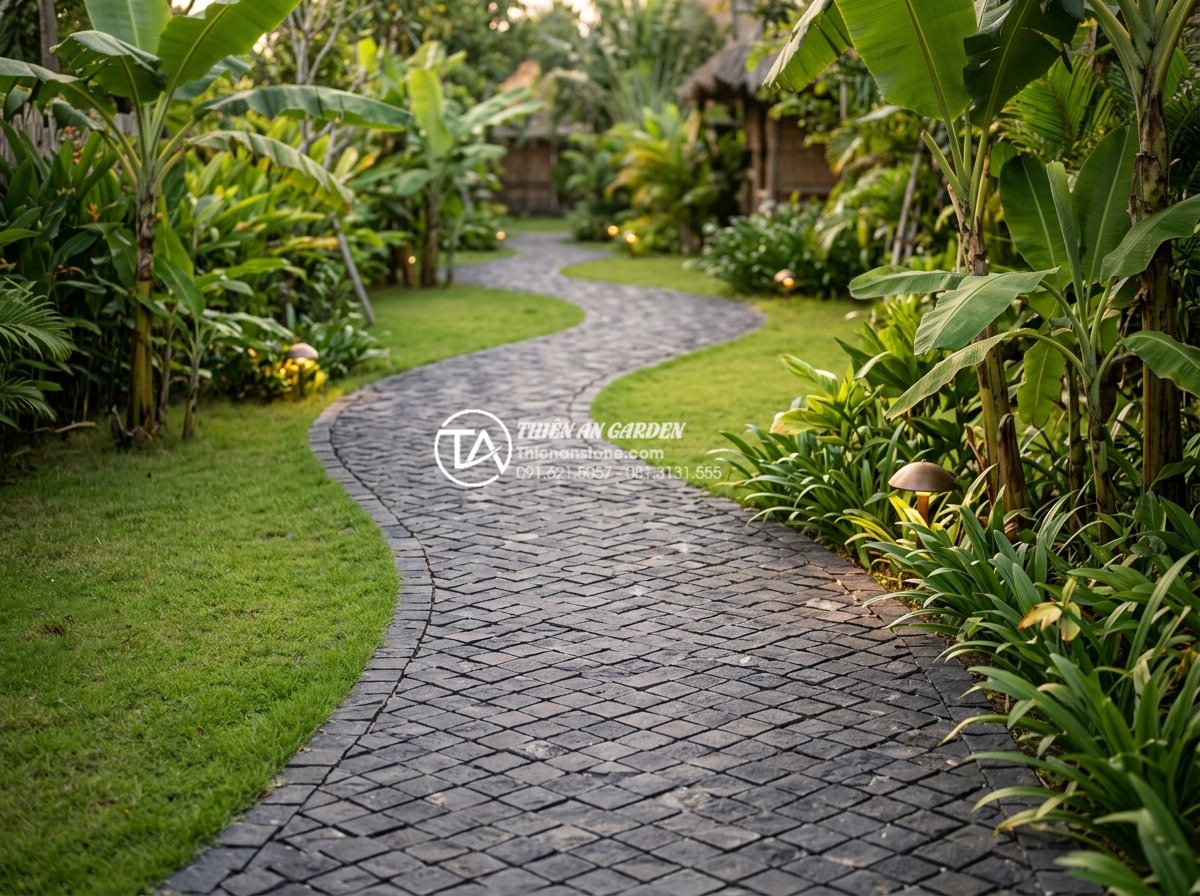 Đá Cubic Lát Sân - Winding garden pathway with cubic stone pavers in herringbone pattern, green law