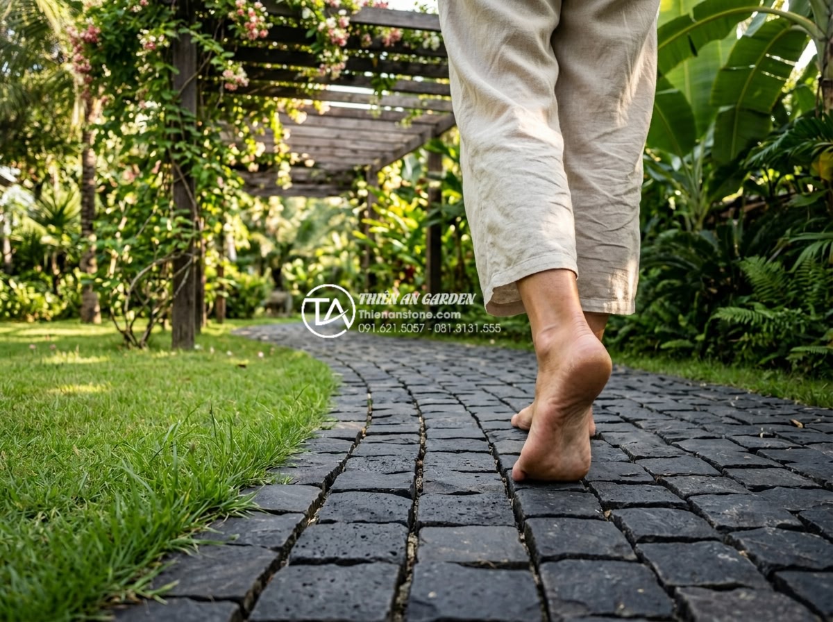Đá Cubic Lát Sân - Person walking barefoot on cubic stone paving in summer garden, warm sunlight fi