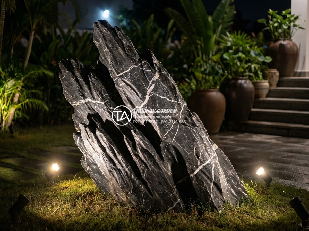 Đá Lũa Đen - Hình 8 Đá Lũa Đen - Black driftwood stone illuminated by warm garden spotlights at night, dramatic s