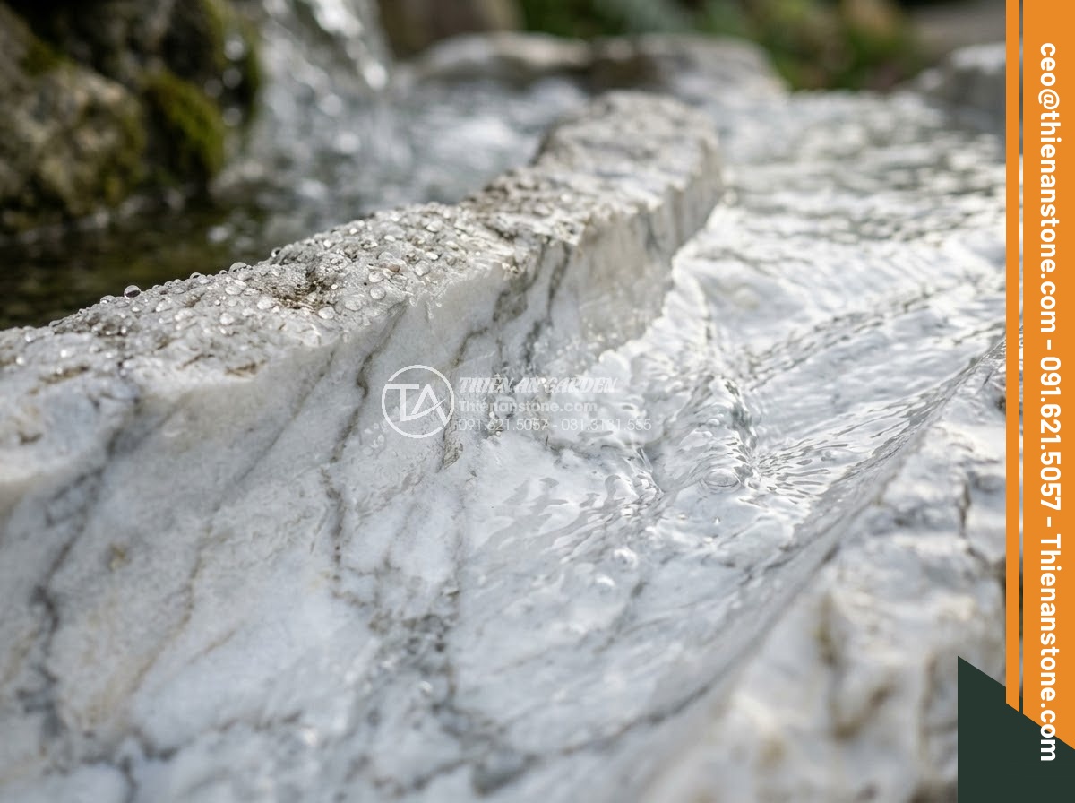 Đài Phun Nước Bằng Đá - Hình 2 Đài Phun Nước Bằng Đá - Close-up of natural stone fountain surface with water flowing over carved granit