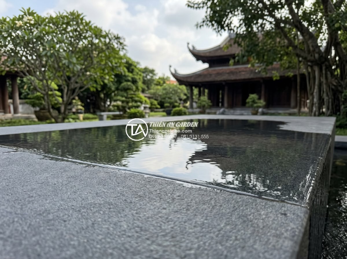 Tiểu Cảnh Nước - Hình 17 Tiểu Cảnh Nước - Side angle view of water film flowing over dark stone surface reflecting sky and