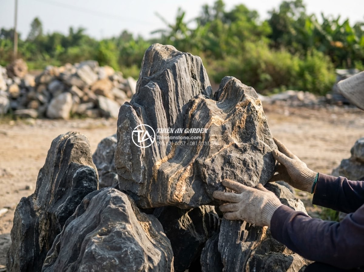 Tiểu Cảnh Thiền (Zen) - Person selecting natural stones at stone yard for zen garden project, hands touc