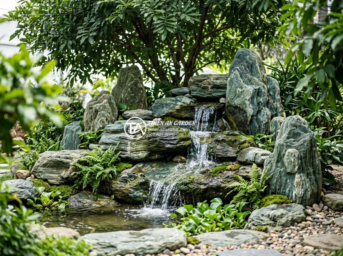 Có nên làm tiểu cảnh nước dưới gốc cây? Ưu và nhược điểm cần biết - Hình 10 Có nên làm tiểu cảnh nước dưới gốc cây? Ưu và nhược điểm cần biết - Expertly arranged natural stone water cascade under a large tree, showing perfec