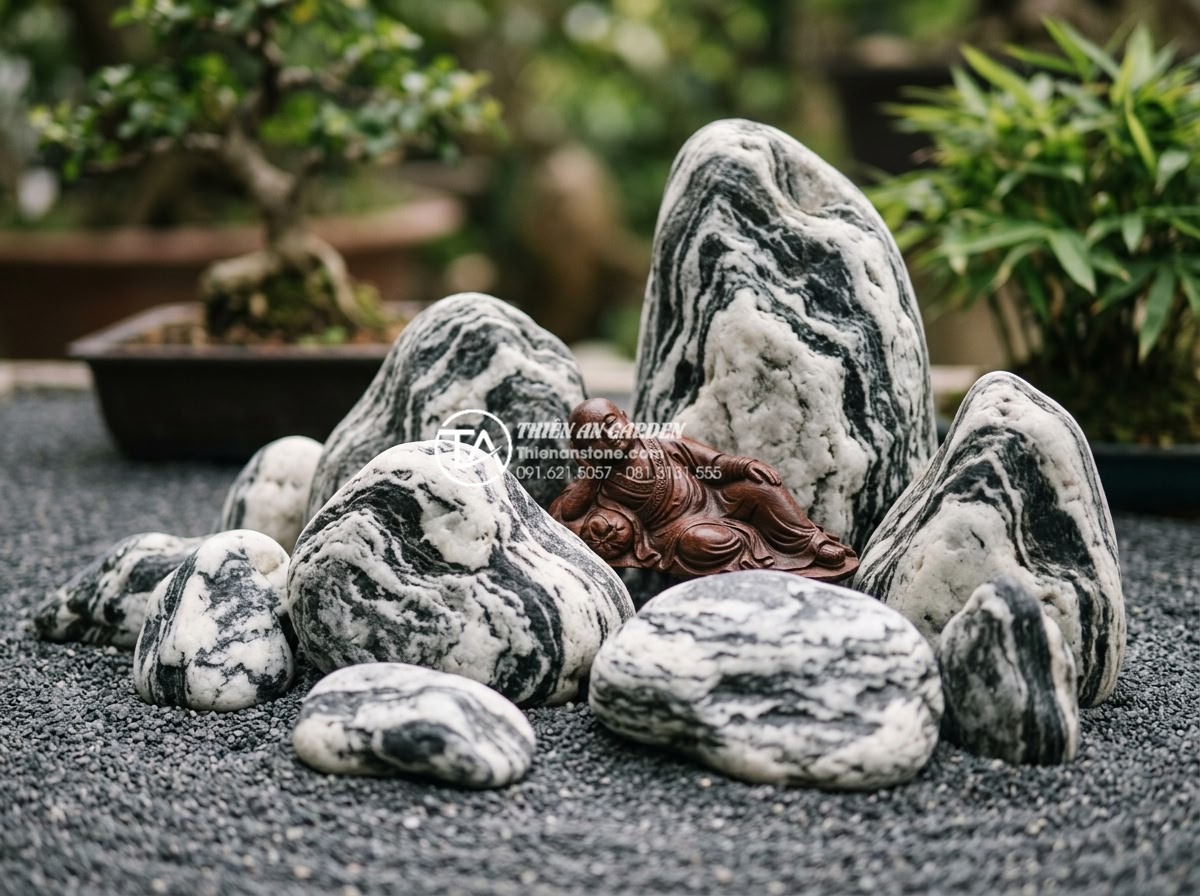 Nghệ thuật sắp đặt sỏi và đá cuội xung quanh tiểu cảnh chú tiểu thiền - Detailed close-up of various natural pebble types suitable for Zen garden: smoot