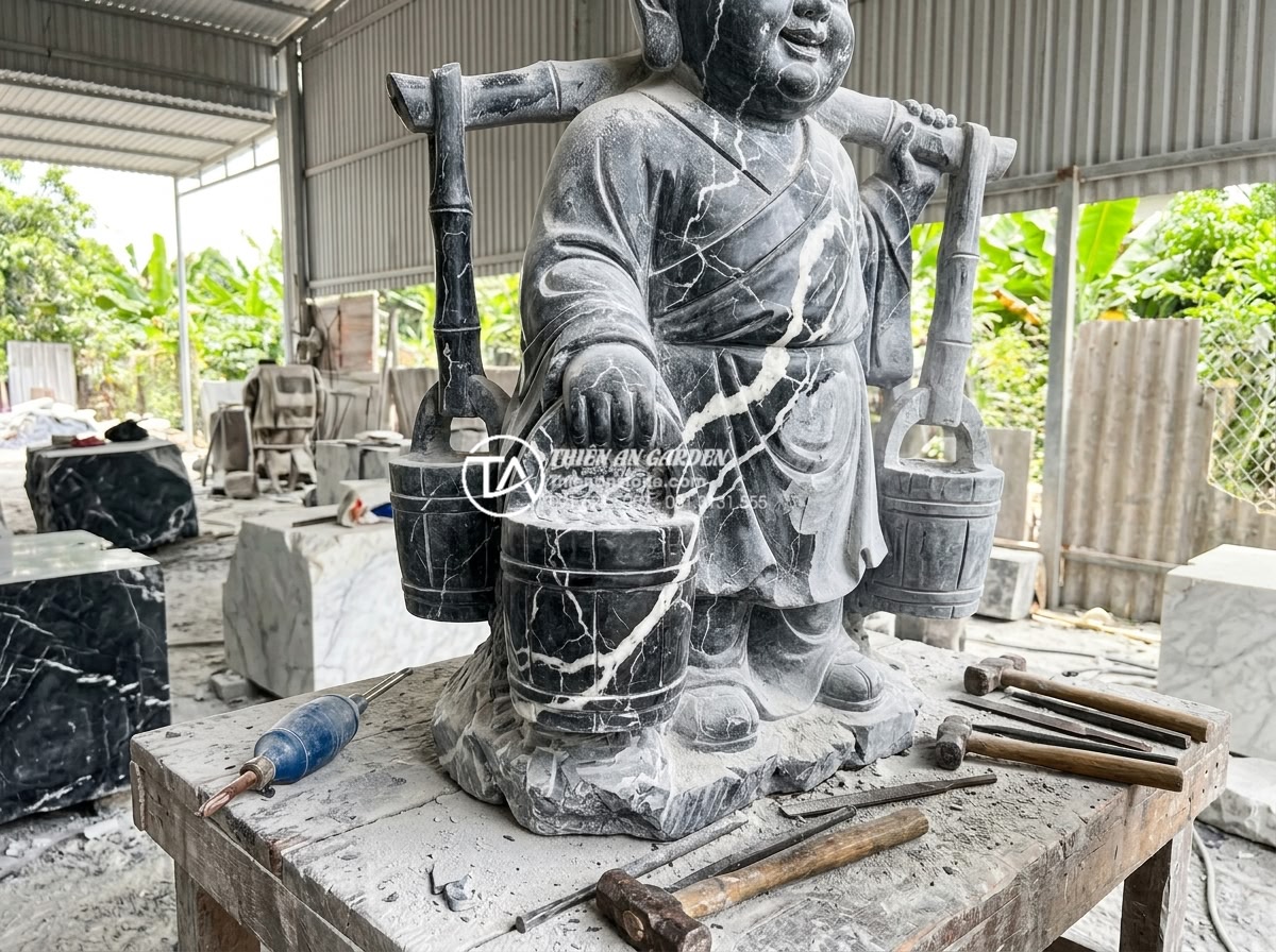 Top 10 mẫu tiểu cảnh chú tiểu gánh nước mang ý nghĩa tài lộc dồi dào - Hình 7 Top 10 mẫu tiểu cảnh chú tiểu gánh nước mang ý nghĩa tài lộc dồi dào - Realistic image of expert stone carvers at a Vietnamese workshop hand-finishing