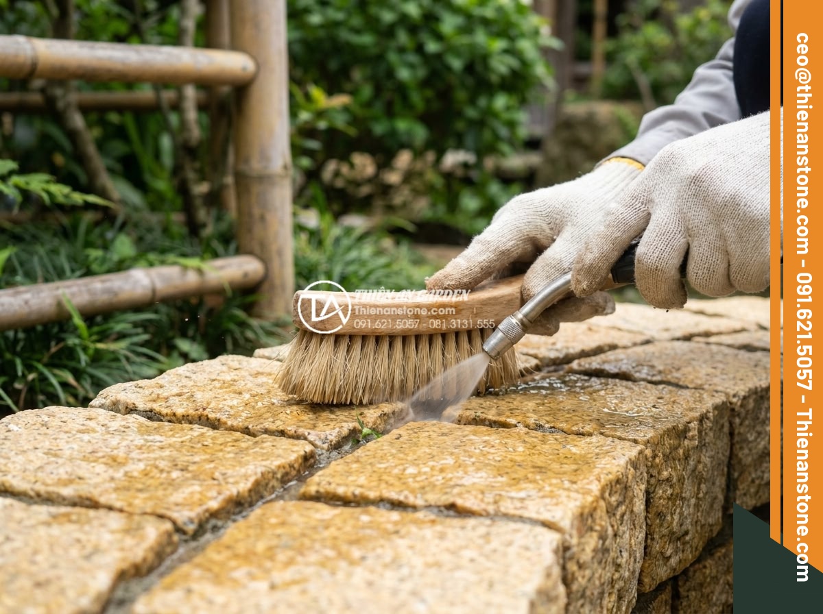 Báo giá đá cubic lát sân mới nhất 2026: Đơn giá theo m2 và chi phí thi công - Hình 19 Báo giá đá cubic lát sân mới nhất 2026: Đơn giá theo m2 và chi phí thi công - Close-up of proper maintenance technique - worker carefully cleaning cubic stone
