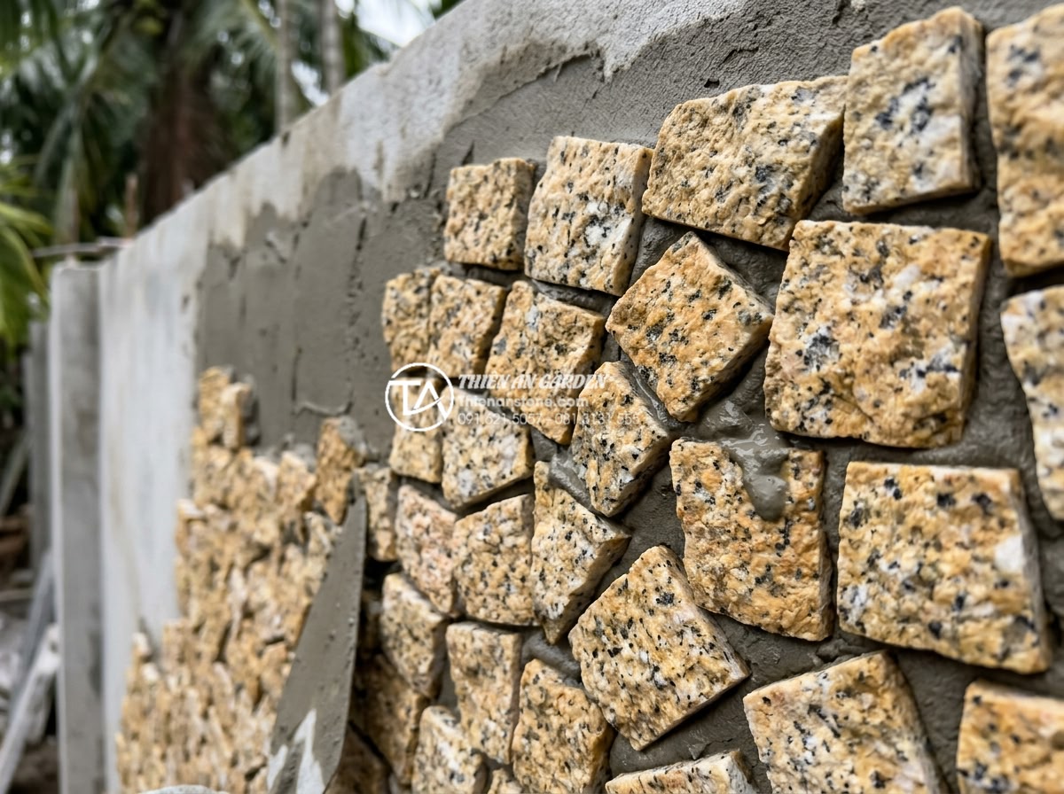 Tại sao nên dùng ốp gạch rối thay vì gạch men thông thường? - Close-up view of natural stone mosaic tiles known as op gach roi being installed