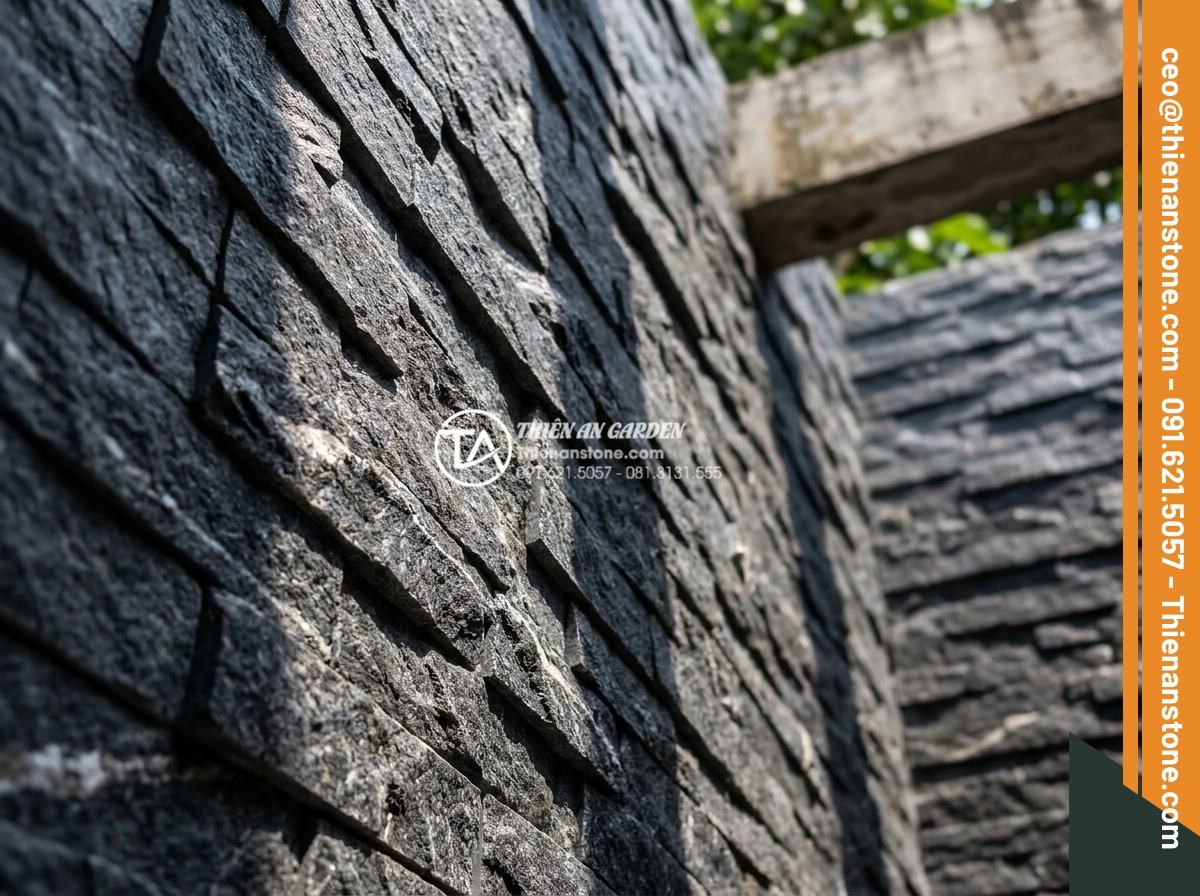 Kinh nghiệm chọn đá ghép đen ốp giếng trời tạo chiều sâu cho không gian - Close-up view of textured black natural pebble stacked stone cladding on skywell