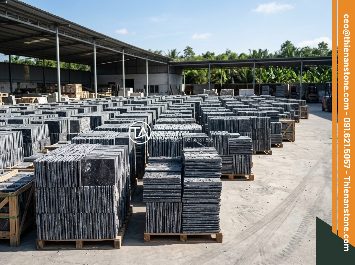 Mua đá ghép ở đâu giá sỉ? Tổng kho đá ghép tự nhiên lớn nhất 3 miền - Hình 2 Mua đá ghép ở đâu giá sỉ? Tổng kho đá ghép tự nhiên lớn nhất 3 miền - Wide angle shot of stacked natural stone mosaic slabs in a large outdoor warehou