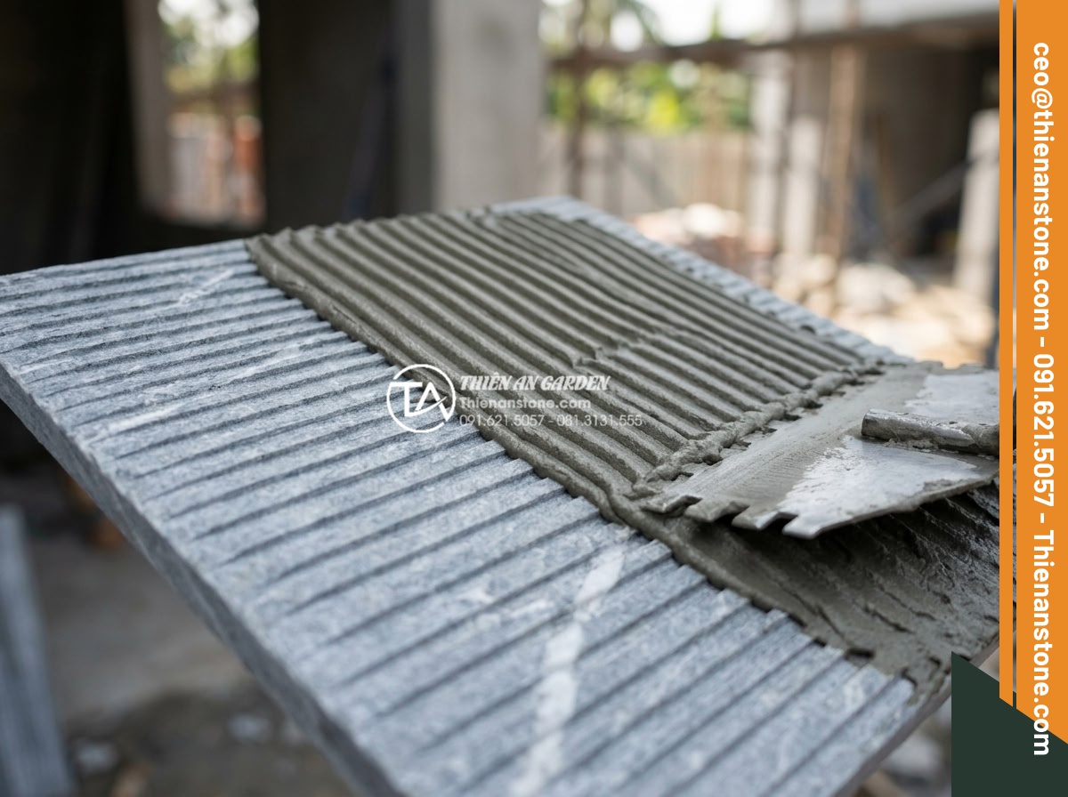 Nên dùng keo dán đá hay xi măng khi ốp đá răng lược lên tường? - Close-up technical shot of flexible polymer-modified stone adhesive being trowel
