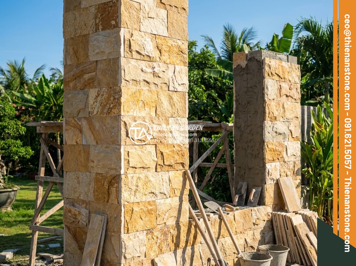 Ứng dụng đá ghép vàng trong thi công trụ cổng và vách ngăn tiểu cảnh - Hình 3 Ứng dụng đá ghép vàng trong thi công trụ cổng và vách ngăn tiểu cảnh - Luxurious golden mosaic stone gate pillar construction in progress with workers