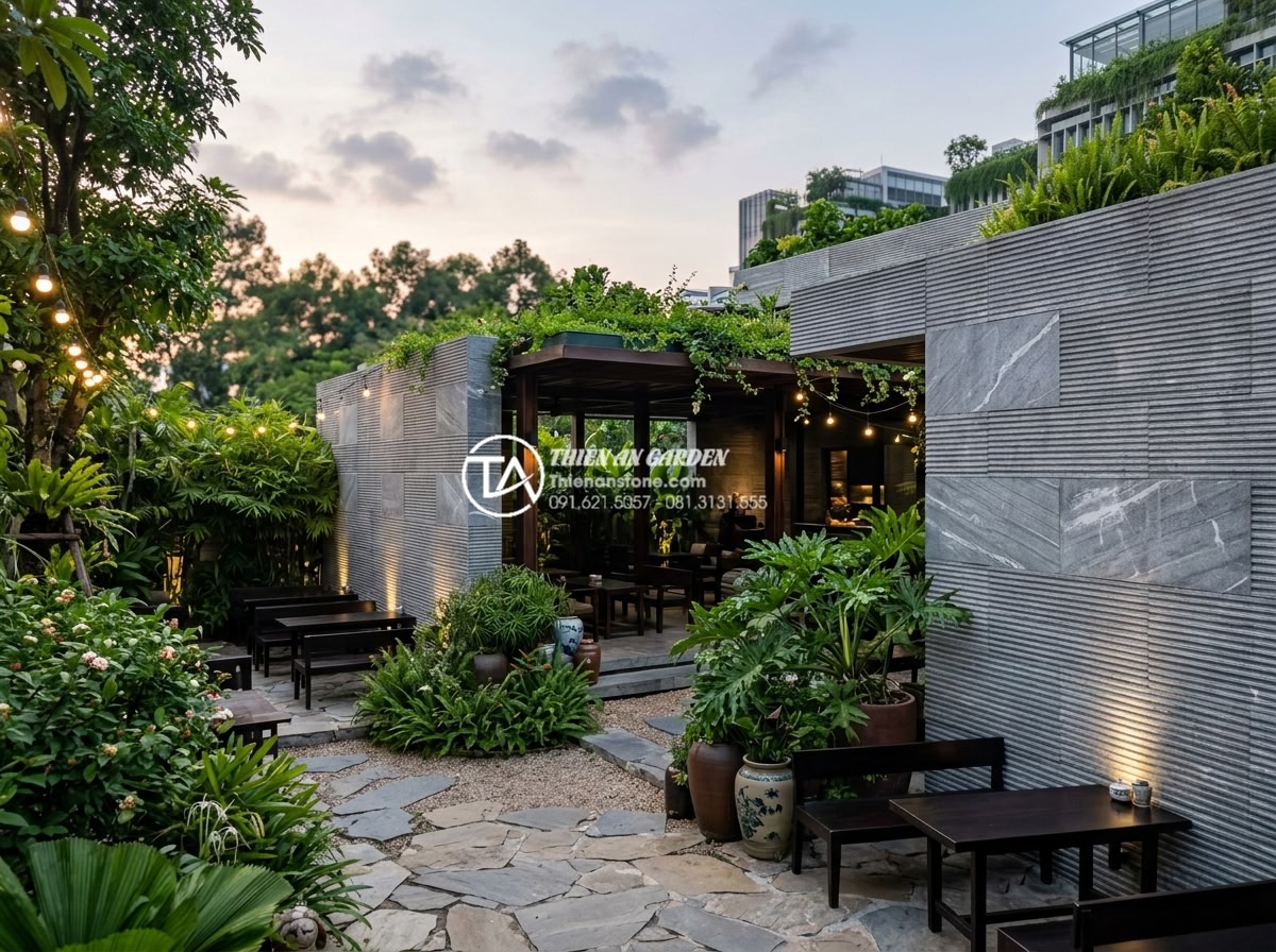 Xu hướng sử dụng đá răng lược trong thiết kế quán cafe sân vườn 2026 - Wide-angle view of a modern garden cafe featuring da rang luoc stone walls, natu