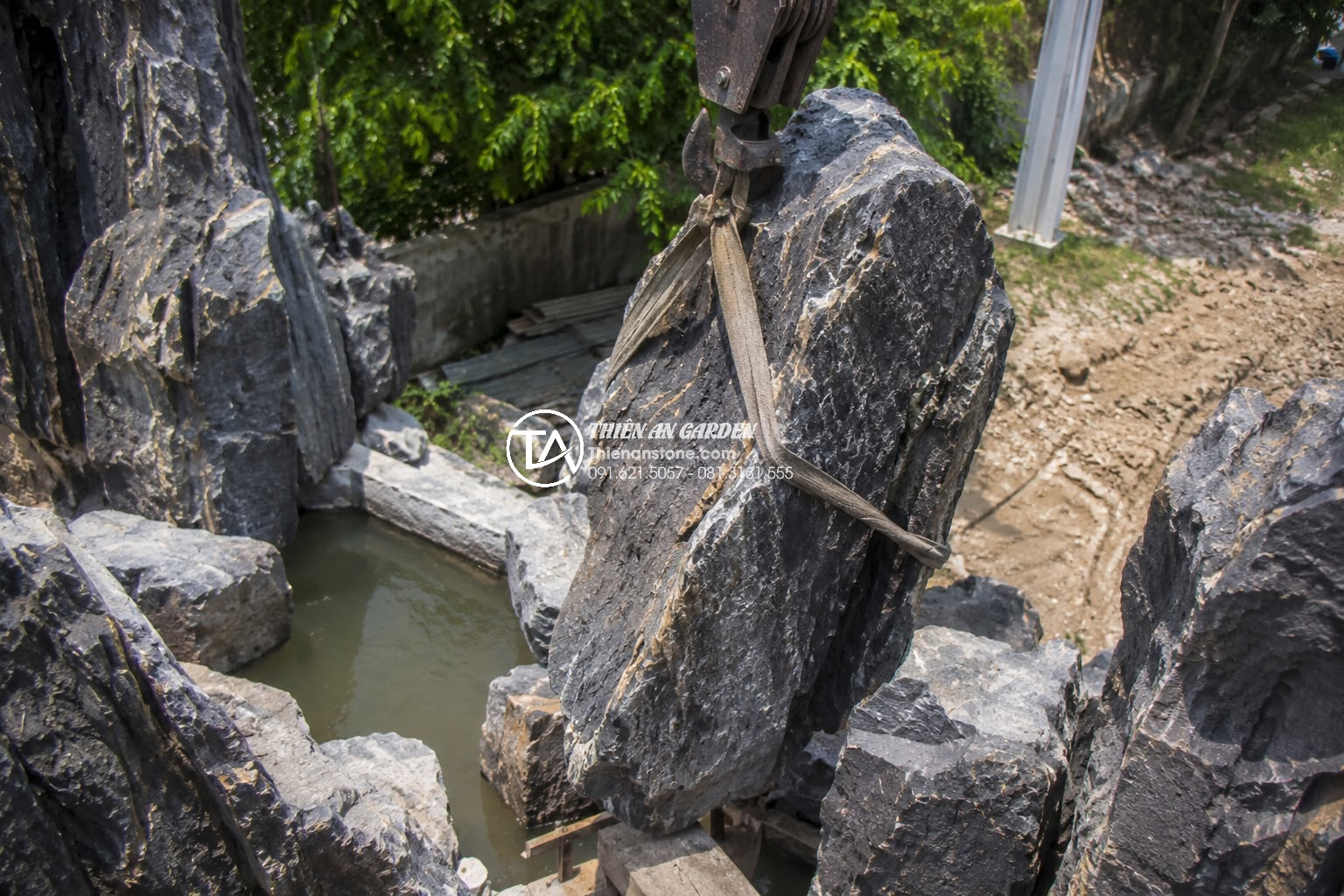 Quy trình thiết kế và thi công tiểu cảnh non bộ chuyên nghiệp từ A-Z - Expert artisans carefully positioning and securing large natural limestone bould