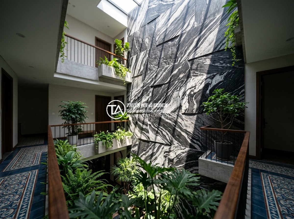 Top 5 loại đá tự nhiên ốp tường giếng trời bền đẹp và sang trọng nhất - Dark basalt natural stone wall cladding in modern sky well atrium with dramatic 