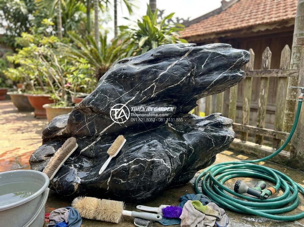 Giải đáp 10 câu hỏi thường gặp (FAQ) về bảo dưỡng tiểu cảnh đá mỹ nghệ - Professional technician cleaning a large stone art rockery with soft brushes and