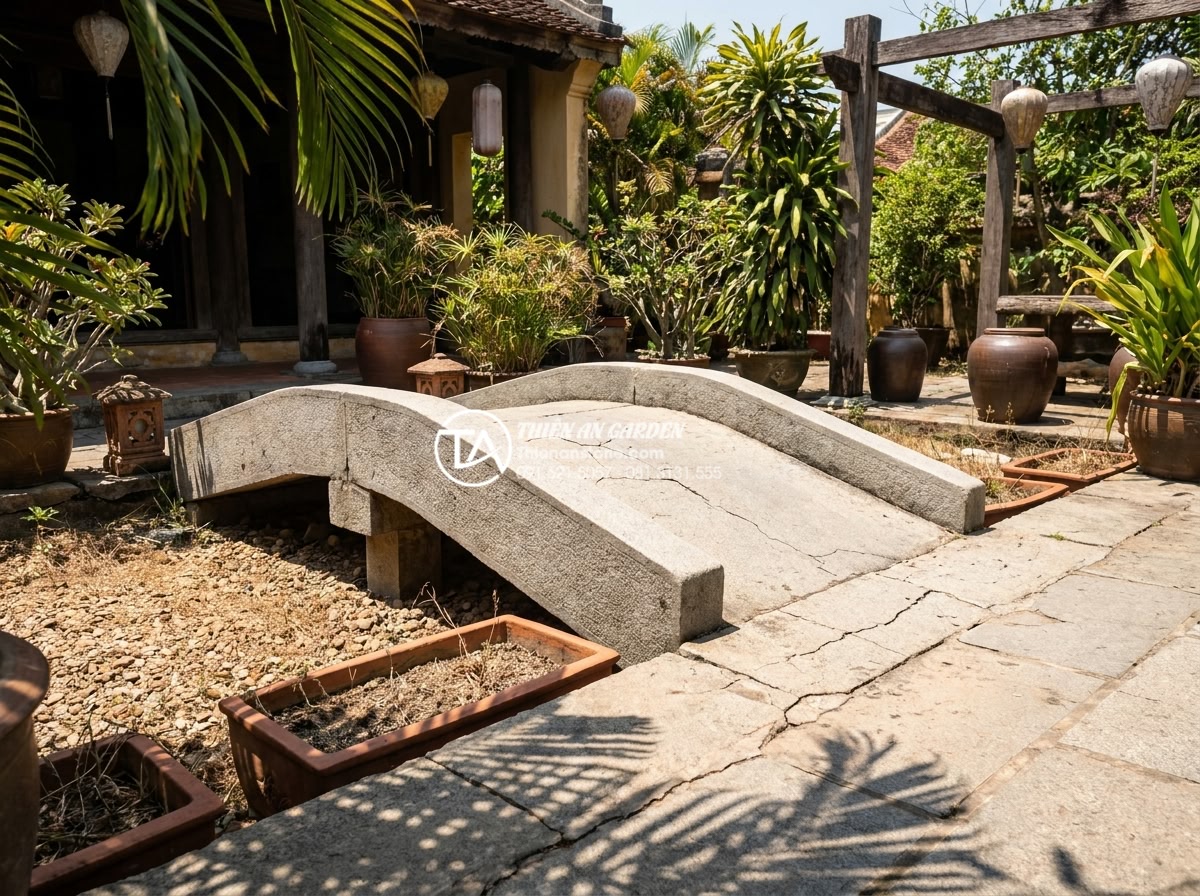 Ảnh hưởng của thời tiết đến độ bền cầu đá và cách bảo quản định kỳ - Sunlit natural stone garden bridge in a Vietnamese villa courtyard during peak s