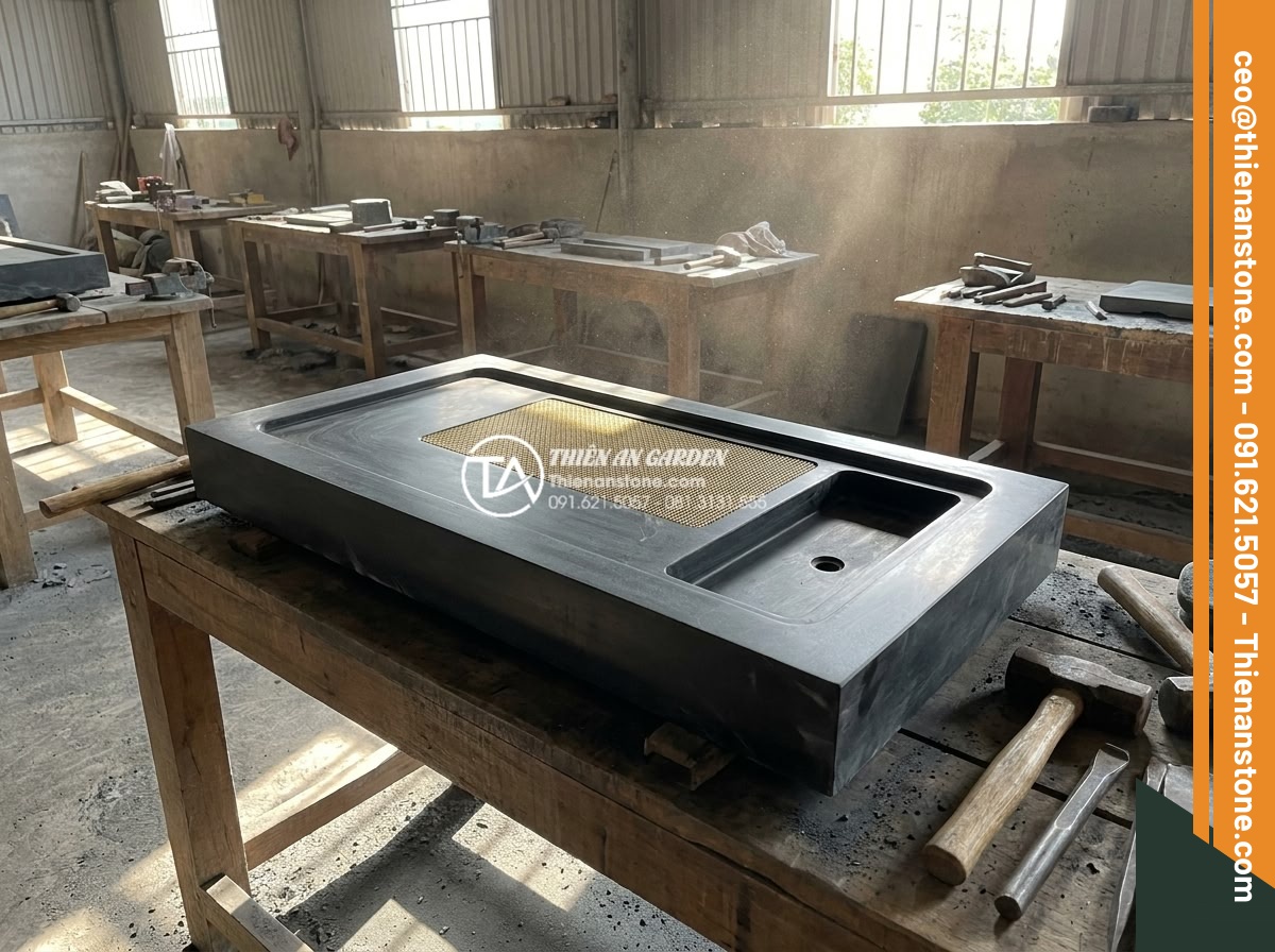 Bàn trà đá bazan (đá đen): Sự lựa chọn tối giản cho không gian hiện đại - Hình 15 Bàn trà đá bazan (đá đen): Sự lựa chọn tối giản cho không gian hiện đại - Professional behind-the-scenes photo of skilled artisans hand-carving a large bl