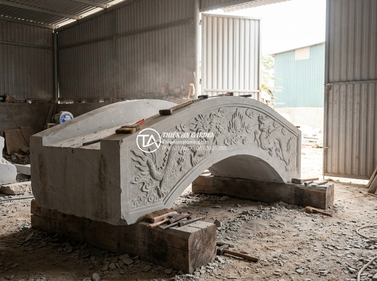 Case study: Cải tạo sân vườn biệt thự 500m2 với điểm nhấn cầu đá nguyên khối - Hình 5 Case study: Cải tạo sân vườn biệt thự 500m2 với điểm nhấn cầu đá nguyên khối - Industrial workshop scene showing artisans hand-carving intricate details on a m