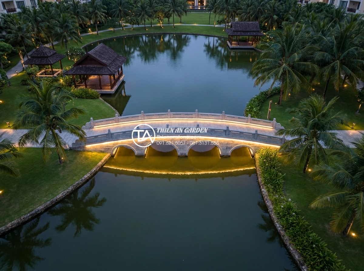 Cầu đá sân vườn một nhịp vs nhiều nhịp: Cách chọn theo diện tích hồ - Hình 5 Cầu đá sân vườn một nhịp vs nhiều nhịp: Cách chọn theo diện tích hồ - Aerial drone-style photograph of a large resort garden pond over 200 square mete