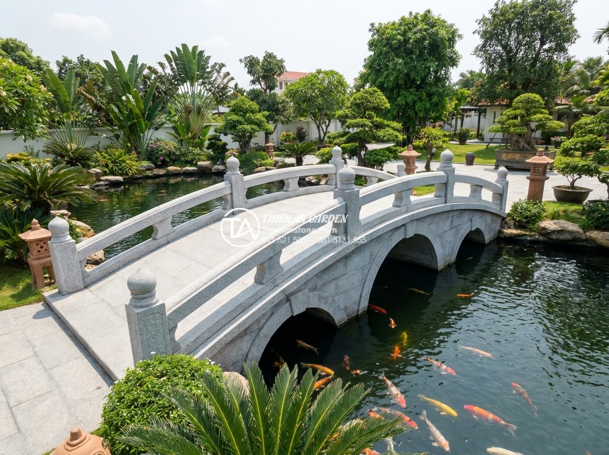 So sánh cầu đá sân vườn và cầu gỗ: Nên chọn loại nào cho hồ cá Koi? - Hình 10 So sánh cầu đá sân vườn và cầu gỗ: Nên chọn loại nào cho hồ cá Koi? - Inspiring hero image of a luxurious completed stone bridge project over a large