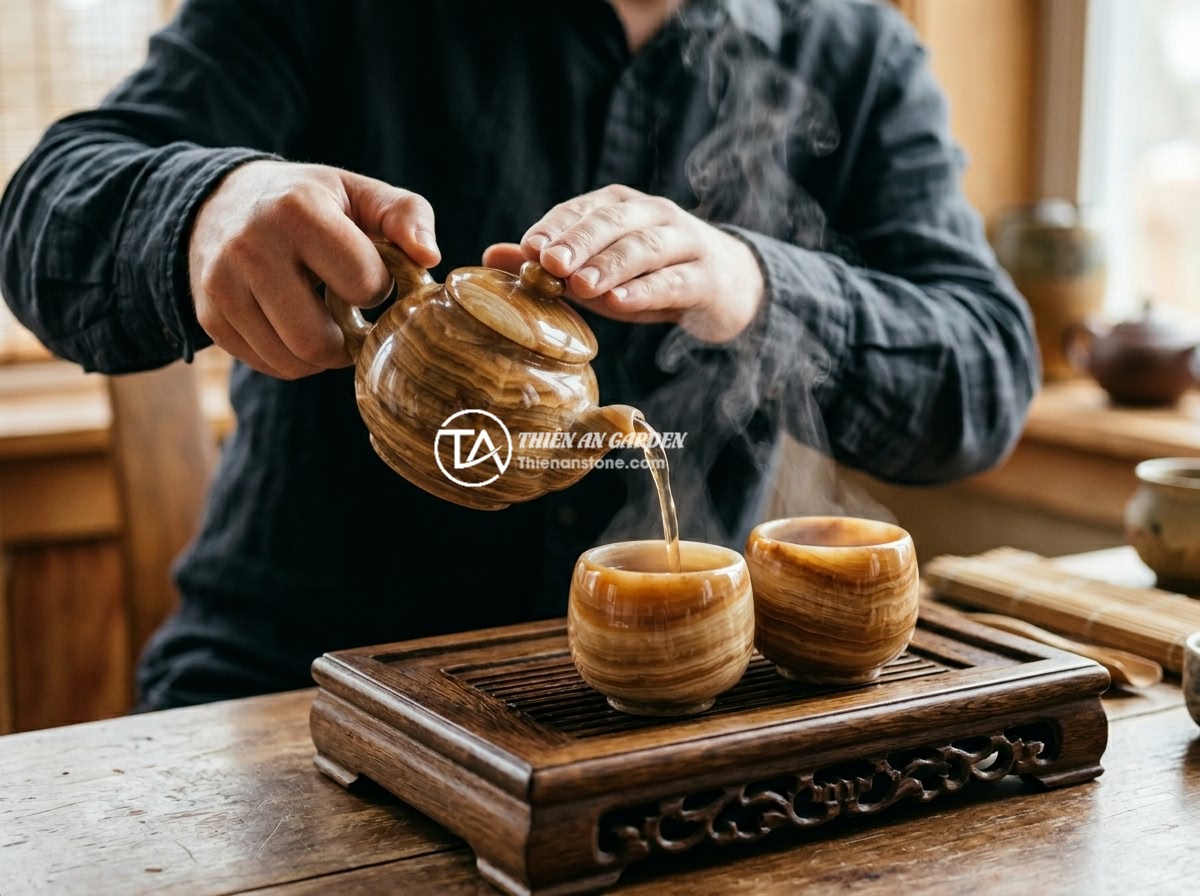 Ấm chén đá tự nhiên giữ nhiệt có tốt không? Đánh giá từ thực tế sử dụng - Hình 3 Ấm chén đá tự nhiên giữ nhiệt có tốt không? Đánh giá từ thực tế sử dụng - A person pouring hot tea from a natural stone teapot into small stone cups on a