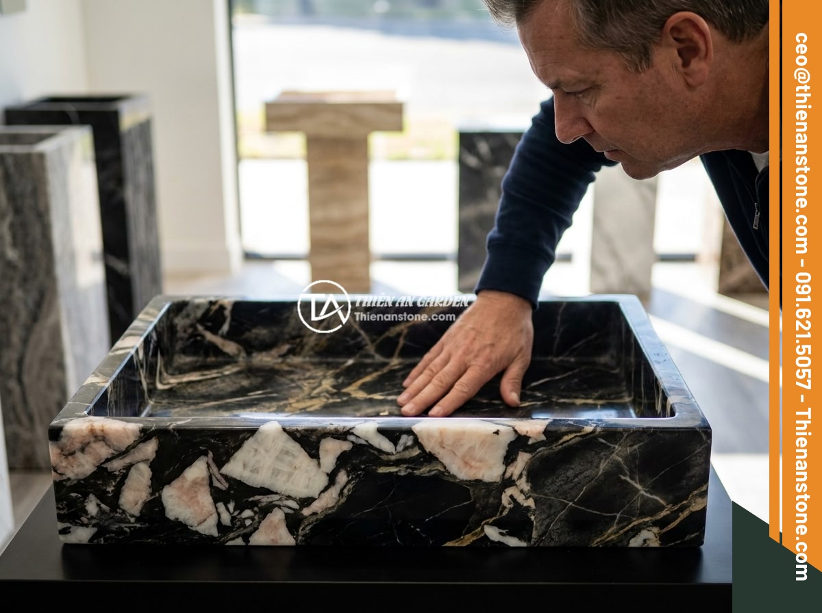 Checklist 10 bước chọn mua đôn đá tự nhiên chất lượng, bền đẹp lâu dài - A homeowner carefully inspecting a natural stone pedestal in a showroom, examini