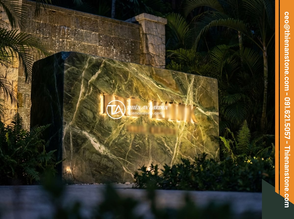 Những biển hiệu độc đáo bằng đá tự nhiên giúp thương hiệu nổi bật giữa đám đông - Hình 3 Những biển hiệu độc đáo bằng đá tự nhiên giúp thương hiệu nổi bật giữa đám đông - An elegant natural stone signage at the entrance of a luxury resort at night, wi