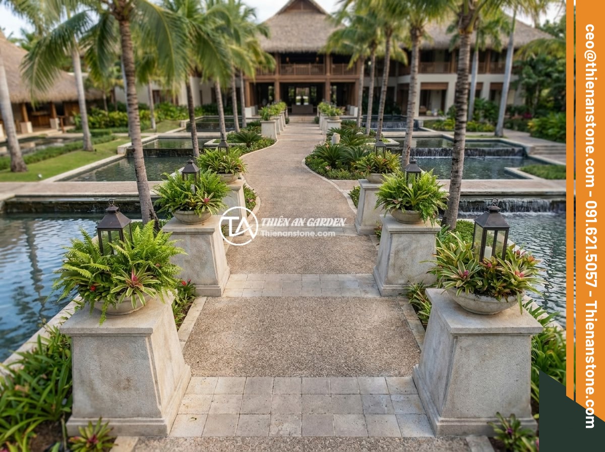 Xu hướng thiết kế đôn đá tự nhiên trong sân vườn biệt thự, resort 2026 - A tropical luxury resort entrance with pairs of natural stone pedestals lining a