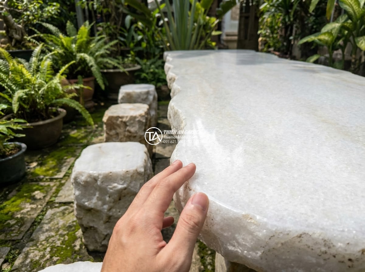 Bàn ghế đá trắng muối - Hình 10 Bàn ghế đá trắng muối - Fingers tracing the edges of a white salt stone table, emphasizing smooth polish