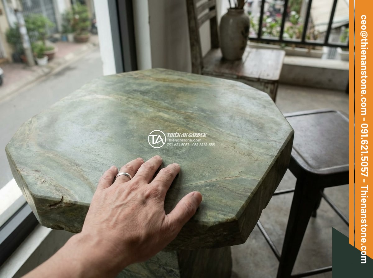 Bàn ghế đá xanh rêu - Hình 9 Bàn ghế đá xanh rêu - Close-up of a person’s hand gently touching the smooth yet textured surface of m