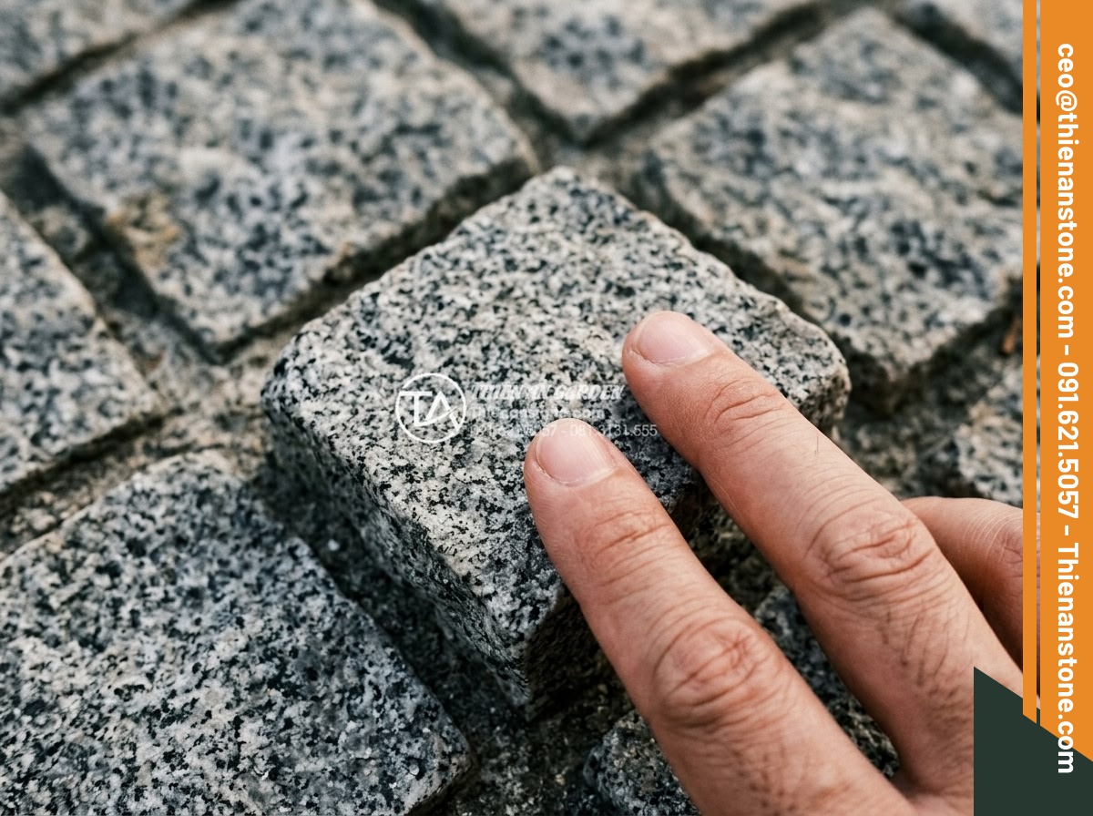 Đá Cubic Granite Muối tiêu - Chất liệu: Đá Granite Muối tiêu tự nhiên - Kích thước: 10x10x5cm (dày 5cm) - Hình 8 Đá Cubic Granite Muối tiêu - Chất liệu: Đá Granite Muối tiêu tự nhiên - Kích thước: 10x10x5cm (dày 5cm) - Close tactile view of granite muoi tieu cubic stone surface with fingers gently