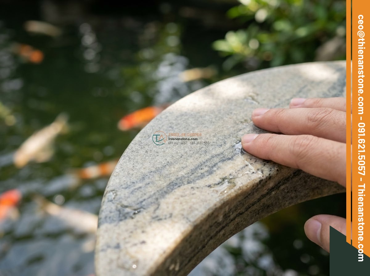 Đèn đá Rankei dáng cong nghệ thuật soi bóng hồ bằng đá Granite cao 120cm. - Hình 3 Đèn đá Rankei dáng cong nghệ thuật soi bóng hồ bằng đá Granite cao 120cm. - Detailed macro photograph of a hand gently touching the smooth polished surface