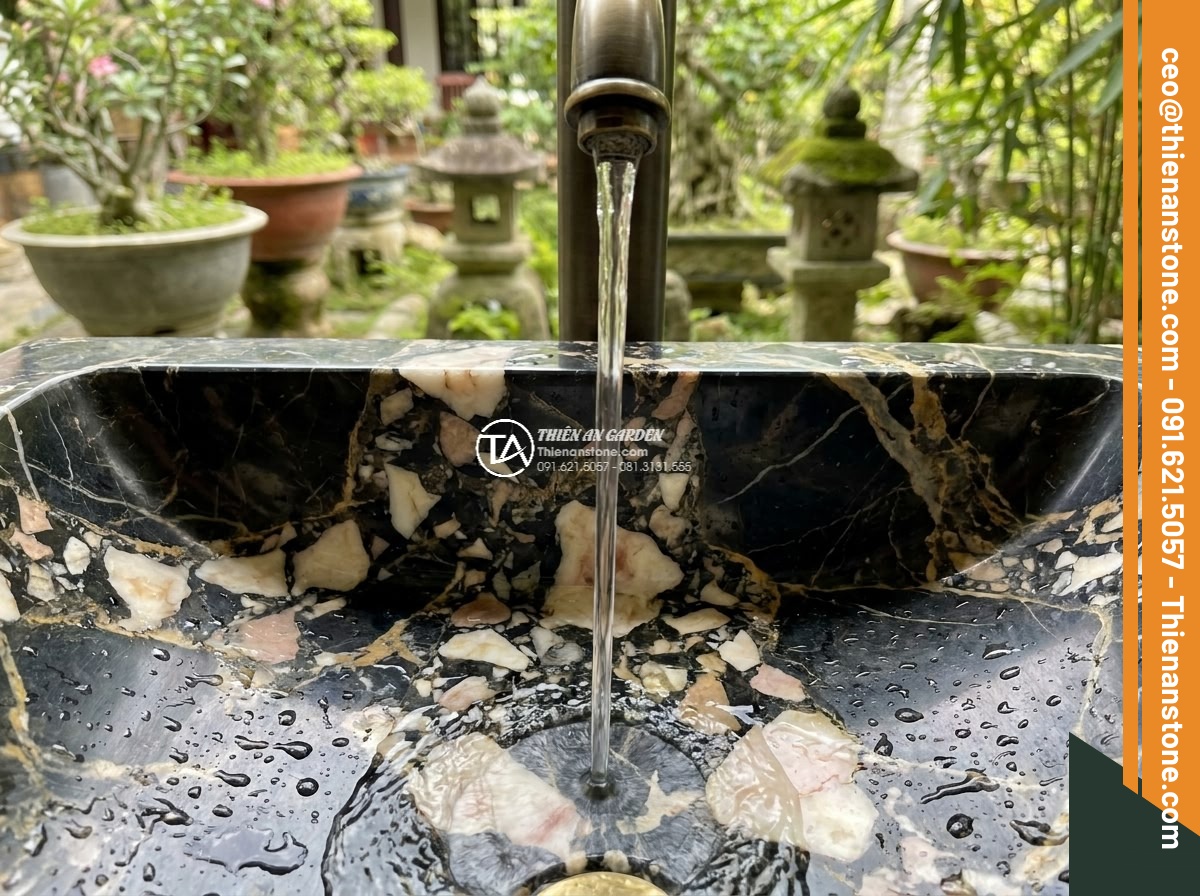 Lavabo đá da báo đỏ tròn phình 42cm (420x420x150mm) - Hình 4 Lavabo đá da báo đỏ tròn phình 42cm (420x420x150mm) - Artistic close-up of water flowing gently into the red leopard stone lavabo sink