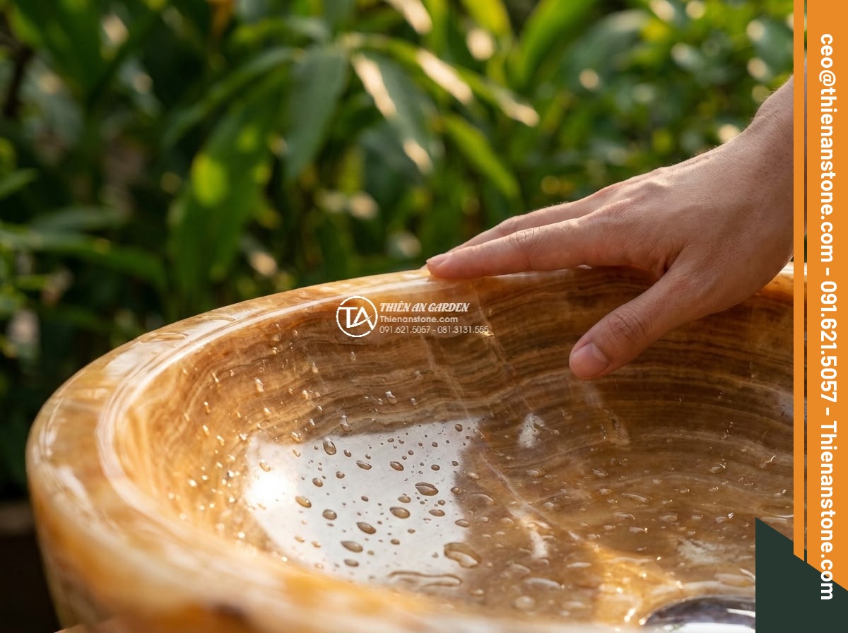 Lavabo đá vân gỗ tròn 42cm (420x420x150mm) - Hình 4 Lavabo đá vân gỗ tròn 42cm (420x420x150mm) - Photorealistic image of a person's hand gently touching the smooth polished surf