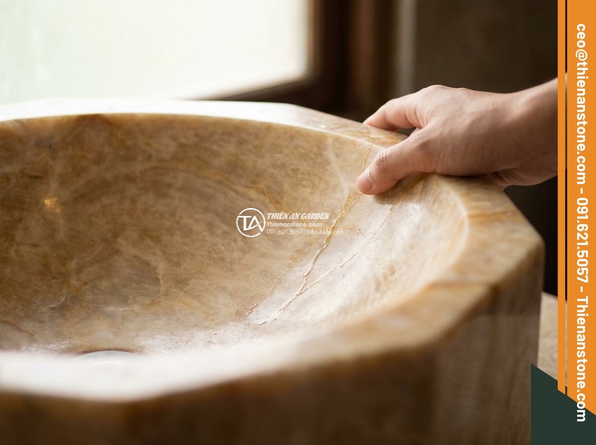 Lavabo đá vàng kim tuyến đa giác (400x400x150mm) - Hình 4 Lavabo đá vàng kim tuyến đa giác (400x400x150mm) - Intimate close-up of a human hand gently touching the polished surface of a gold