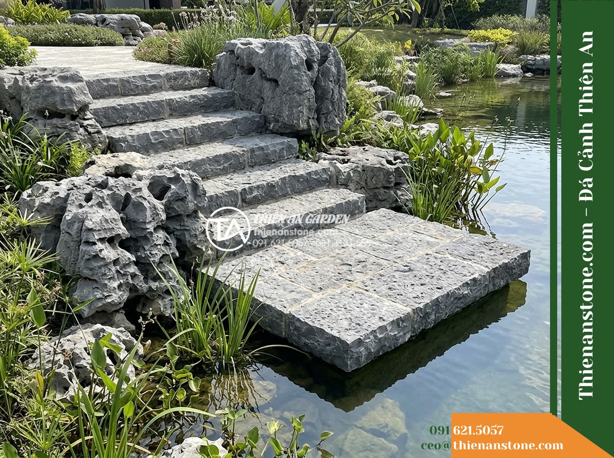 Đá Mão Xám (Khối trung 60–120cm / ~300–900kg) | Chuyên ghép bệ móng vững chãi, tạo thềm đá phẳng sát mặt nước. - Hình 16 Đá Mão Xám (Khối trung 60–120cm / ~300–900kg) | Chuyên ghép bệ móng vững chãi, tạo thềm đá phẳng sát mặt nước. - Wide view of the pond edge showing clear, walkable stone access steps leading na