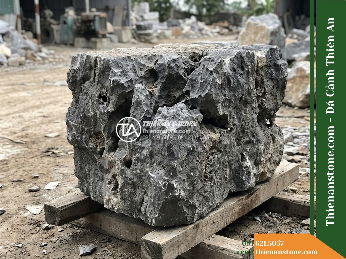 Đá Mão Xám (Khối trung 60–120cm / ~300–900kg) | Chuyên ghép bệ móng vững chãi, tạo thềm đá phẳng sát mặt nước. - Hình 4 Đá Mão Xám (Khối trung 60–120cm / ~300–900kg) | Chuyên ghép bệ móng vững chãi, tạo thềm đá phẳng sát mặt nước. - Side perspective of a raw gray stone block resting on timber skids in a stone wo