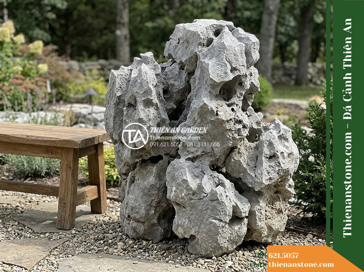 Đá Mão Xám (Khối trung 60–120cm / ~300–900kg) | Chuyên ghép bệ móng vững chãi, tạo thềm đá phẳng sát mặt nước. - Hình 5 Đá Mão Xám (Khối trung 60–120cm / ~300–900kg) | Chuyên ghép bệ móng vững chãi, tạo thềm đá phẳng sát mặt nước. - A natural gray stone block of medium scale positioned beside a low wooden garden
