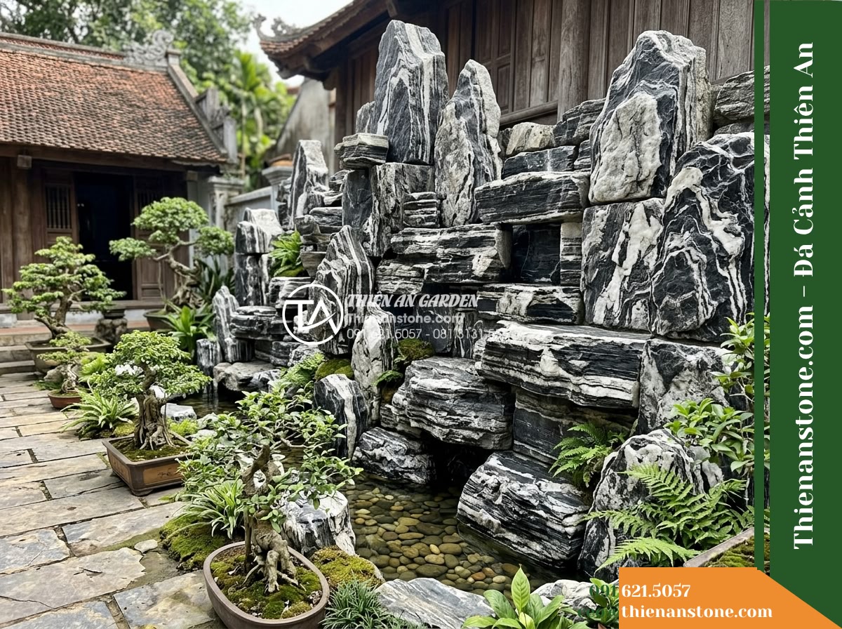 Đá Ngũ Vân Sơn (Size lớn 50–90cm) | Chuyên làm vách đá, non bộ lớn. - A realistic courtyard landscape scene featuring a towering rockery wall construc