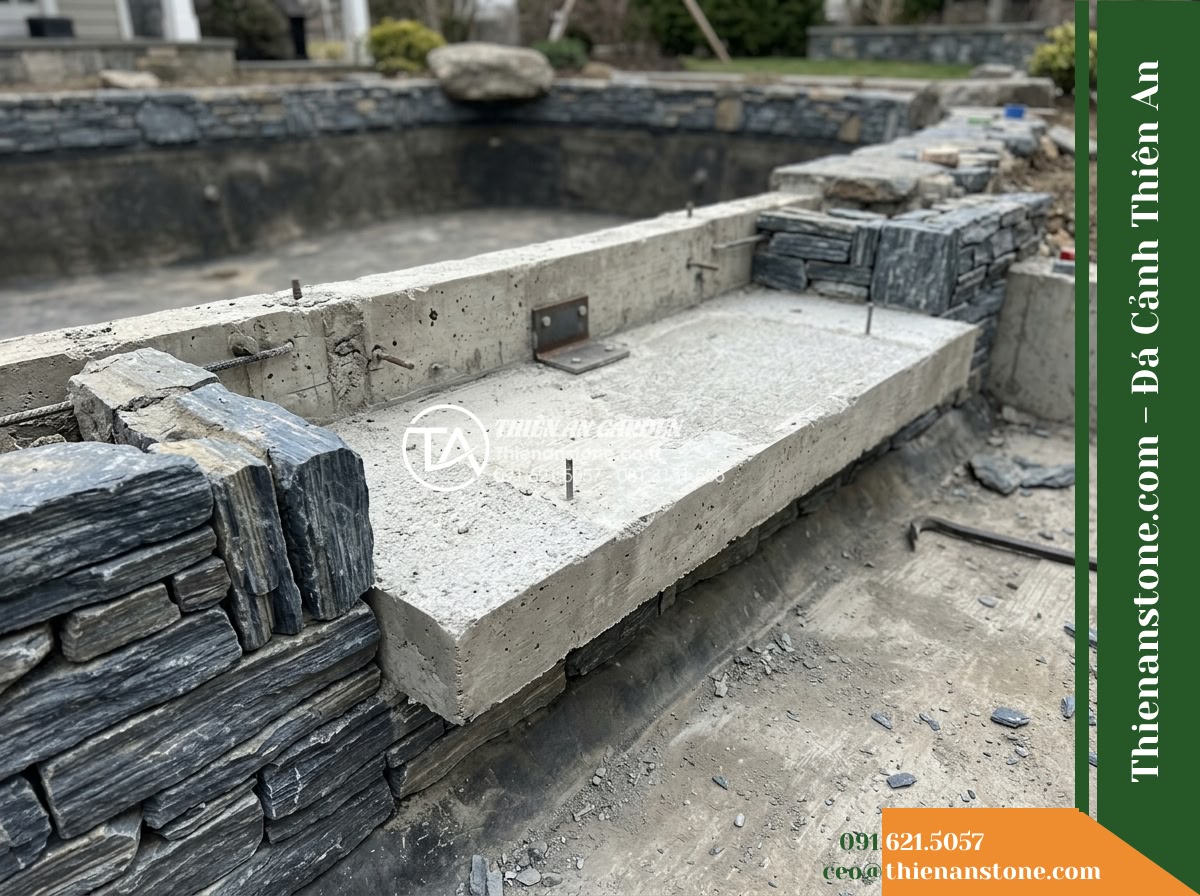 Đá Ông Phú (Khối đại 50–80cm) | Chuyên làm đá chủ, vách núi lớn hồ cá Koi. - Hình 10 Đá Ông Phú (Khối đại 50–80cm) | Chuyên làm đá chủ, vách núi lớn hồ cá Koi. - Close-up view of the reinforced concrete base shelf along a pond edge, showing t