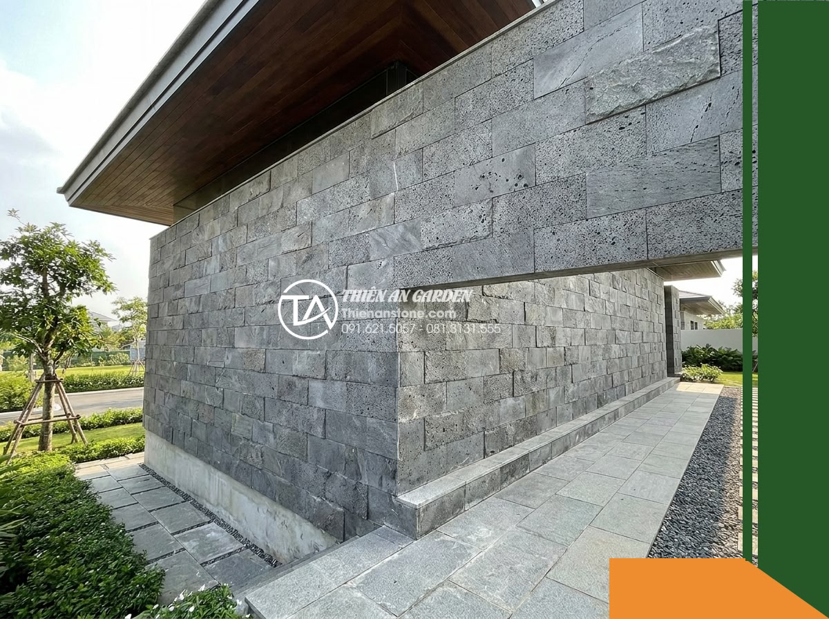 Đá răng lược bazan Gia Lai | Bazan xám đen Gia Lai | 10x50 cm - Hình 16 Đá răng lược bazan Gia Lai | Bazan xám đen Gia Lai | 10x50 cm - A wider shot of the full height of an exterior cladded basalt wall showing the u