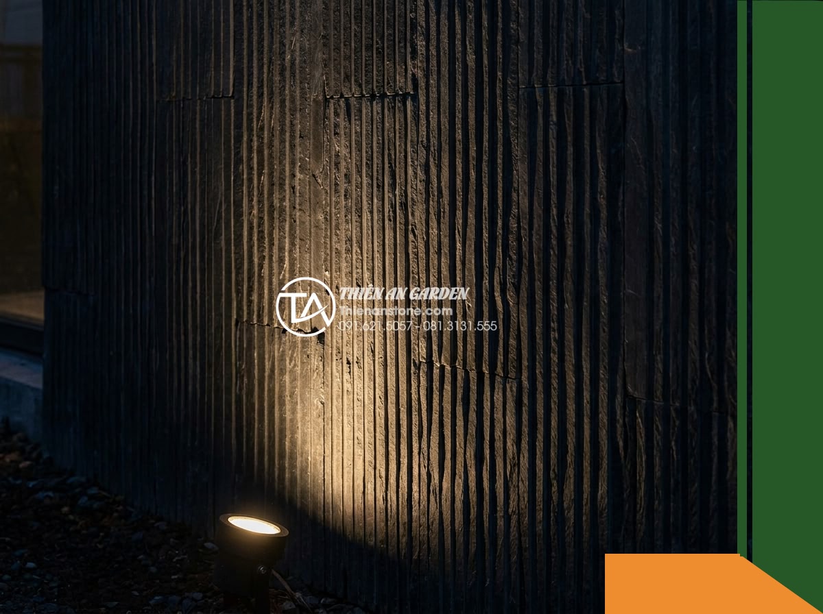Đá răng lược đen Tuyên Quang | Slate đen tuyền Tuyên Quang | 10x50 cm - Hình 14 Đá răng lược đen Tuyên Quang | Slate đen tuyền Tuyên Quang | 10x50 cm - An evening scene showing the same black comb-cut slate wall softly illuminated b