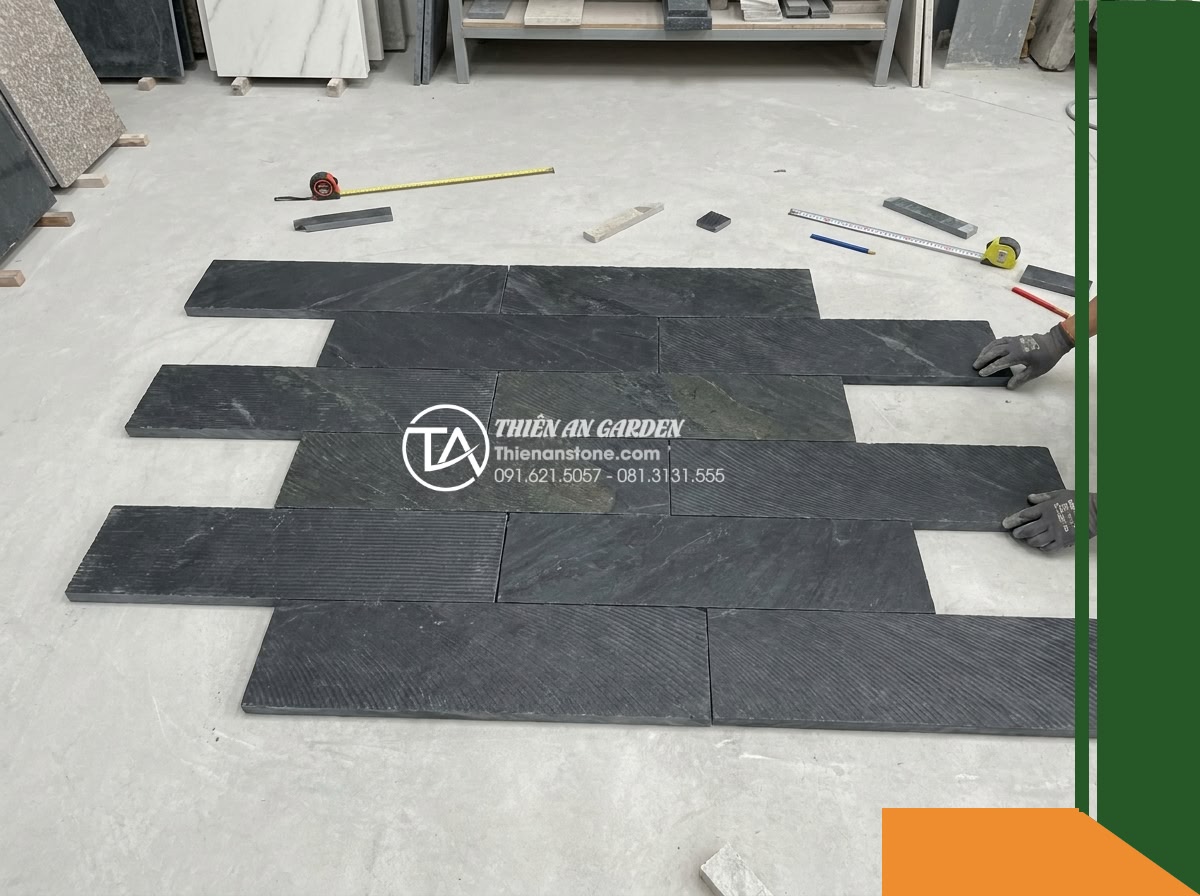 Đá răng lược đen Tuyên Quang | Slate đen tuyền Tuyên Quang | 10x50 cm - Hình 7 Đá răng lược đen Tuyên Quang | Slate đen tuyền Tuyên Quang | 10x50 cm - A high-angle shot of a mock-up dry-lay test on a smooth workshop floor, showing