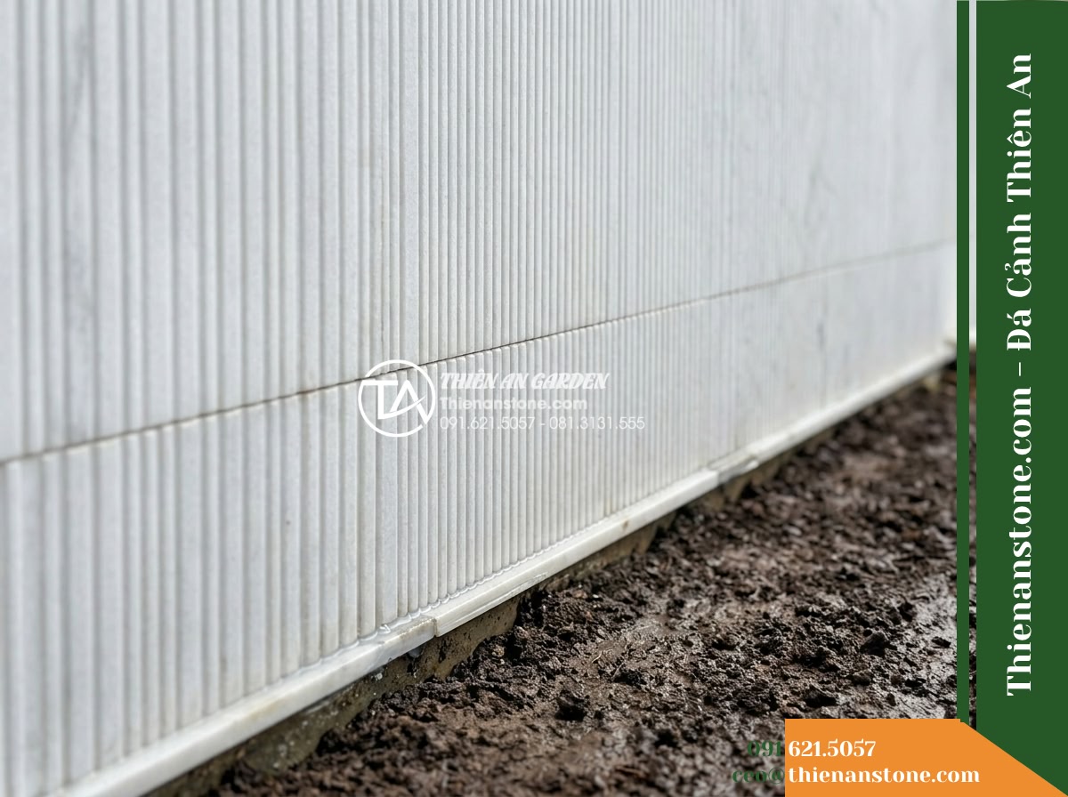 Đá răng lược trắng Nghệ An | Marble trắng Nghệ An | 10x50 cm - Hình 9 Đá răng lược trắng Nghệ An | Marble trắng Nghệ An | 10x50 cm - Architectural junction detail where a white combed marble wall meets the damp to