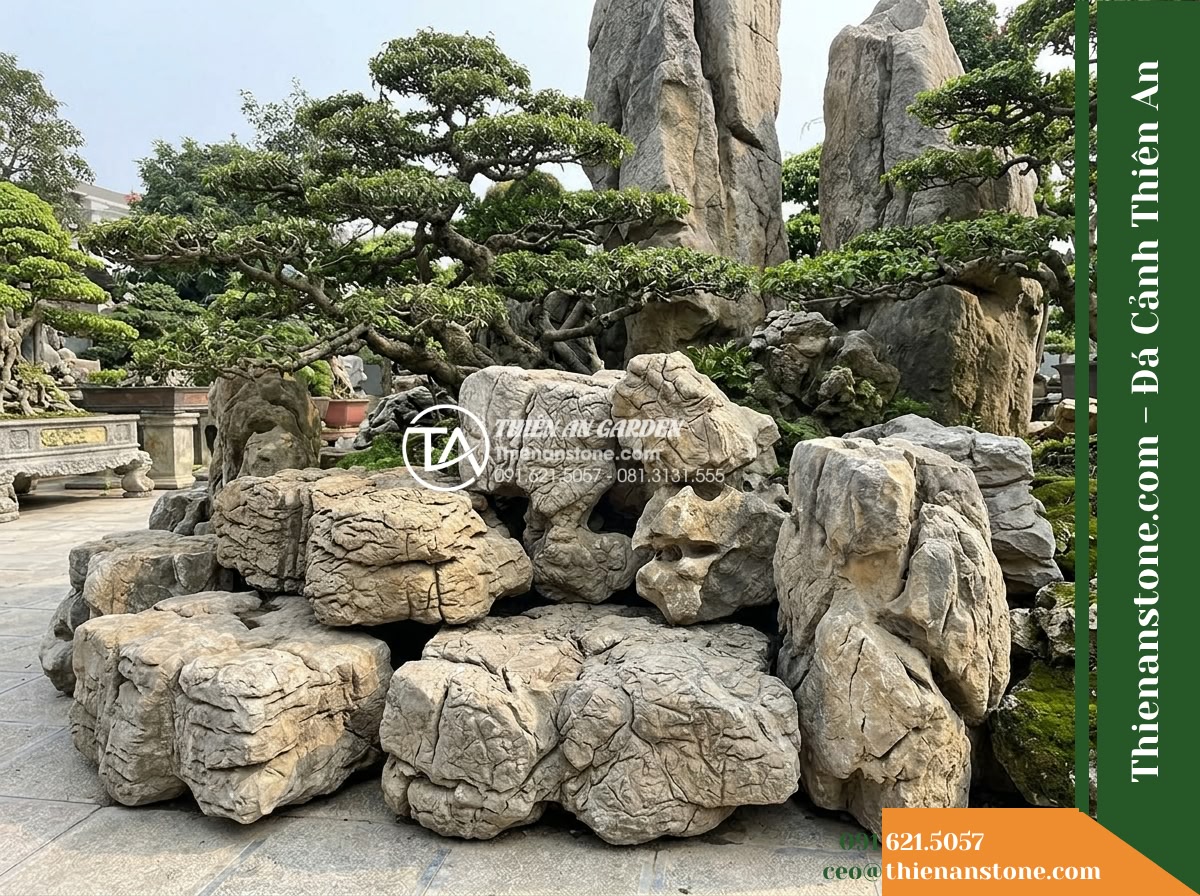 Đá Tượng Sáp (Khối trung 80–120cm / ~0.5–1.2 tấn) | Chuyên xếp chân núi, tạo các hốc luồn lách để trồng cây cảnh lớn, bonsai cổ thụ. - Hình 12 Đá Tượng Sáp (Khối trung 80–120cm / ~0.5–1.2 tấn) | Chuyên xếp chân núi, tạo các hốc luồn lách để trồng cây cảnh lớn, bonsai cổ thụ. - Contextual view of an assembled rockery section showing how medium-sized stones
