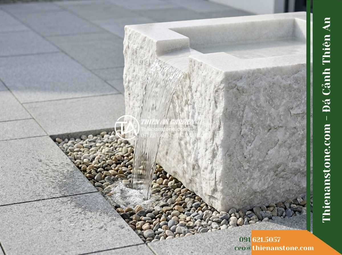 Đài Phun Bát Vuông Lòng Mài Mịn Vỏ Thô, Bát D80cm Cao 75cm - Hình 8 Đài Phun Bát Vuông Lòng Mài Mịn Vỏ Thô, Bát D80cm Cao 75cm - Side profile view of water spilling over square stone edges into a hidden gravel
