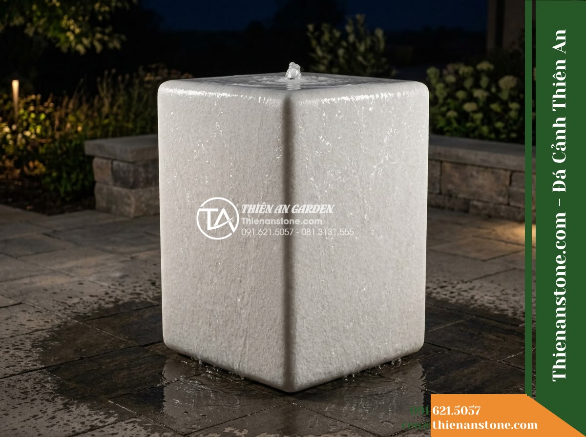 Đài Phun Khối Bo Vuông Khò Mặt Nước, 60x60cm Cao 90cm - Hình 14 Đài Phun Khối Bo Vuông Khò Mặt Nước, 60x60cm Cao 90cm - Atmospheric night shot of the rounded stone water feature illuminated by subtle