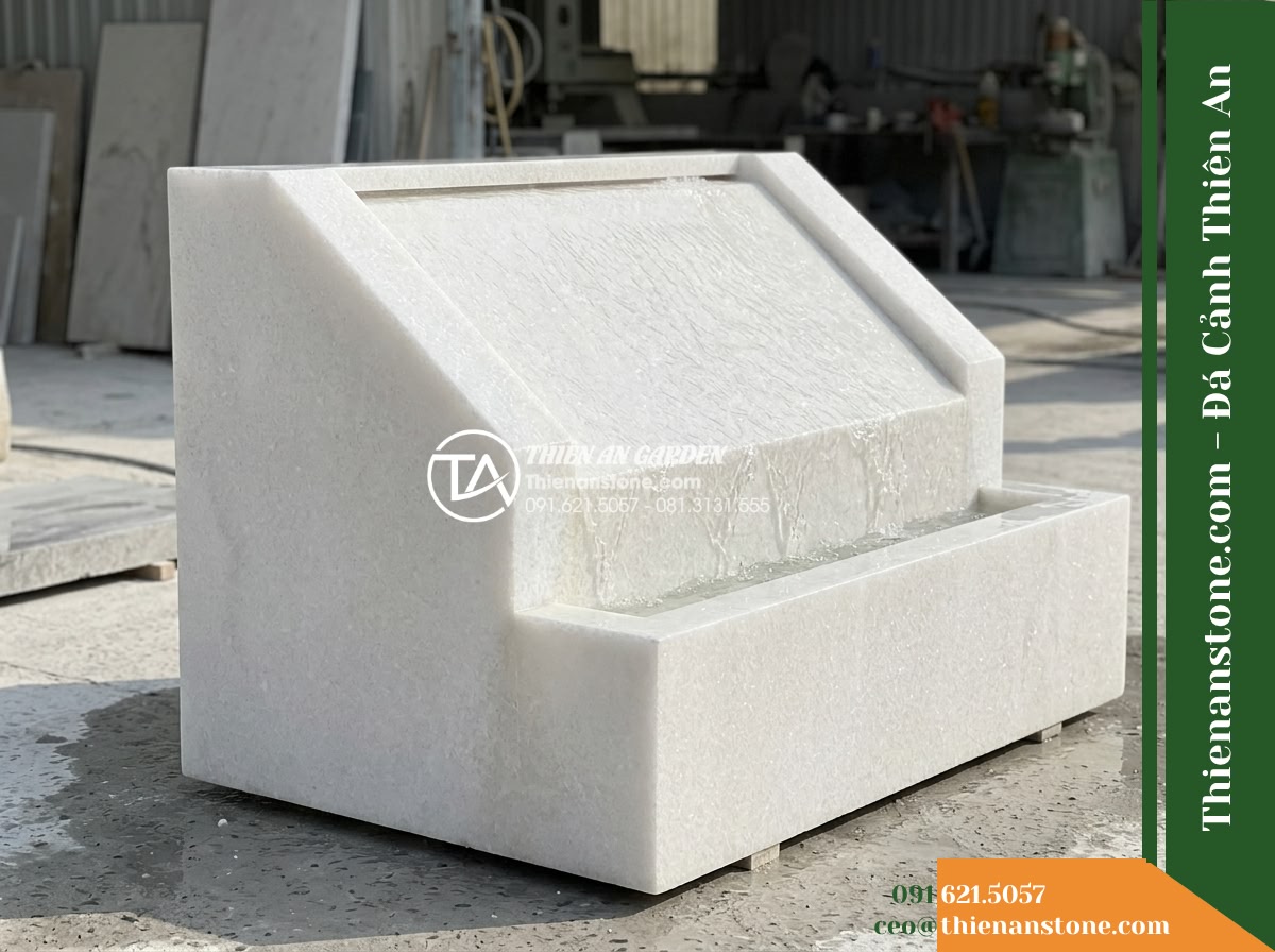 Đài Phun Khối Suối Dốc Chảy Róc Rách, D90cm Cao 85cm - Hình 11 Đài Phun Khối Suối Dốc Chảy Róc Rách, D90cm Cao 85cm - A standalone display photograph of the D90cm H85cm sloped stone fountain in an o